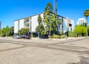 Thumbnail 4 of 4 - A modern building with a white facade is surrounded by palm trees and other greenery.