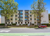 Thumbnail 1 of 8 - A red car is parked in front of a building with a sign that reads "PATRIARCH".