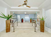 Thumbnail 4 of 8 - A hallway with a ceiling fan and potted plants.