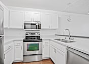 Thumbnail 3 of 11 - A modern kitchen with white cabinets and stainless steel appliances.