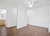 Thumbnail 4 of 11 - A room with a ceiling fan and wooden flooring.