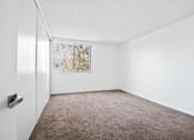 Thumbnail 5 of 11 - A room with a carpeted floor and a window with a view of trees.