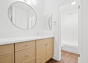 Thumbnail 6 of 11 - A bathroom with a mirror, sink, and wooden cabinets.