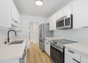 Thumbnail 25 of 56 - A kitchen with white cabinets and appliances.