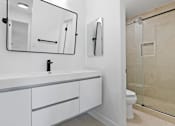 Thumbnail 28 of 56 - A white bathroom with a sink, mirror, toilet and shower.