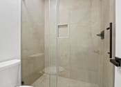 Thumbnail 29 of 56 - A white bathtub sits next to a glass shower door.