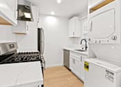 Thumbnail 3 of 11 - A white kitchen with a black stove top and a white oven.