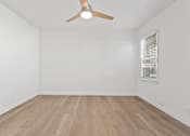 Thumbnail 5 of 11 - A room with a ceiling fan and wooden flooring.