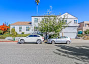 Thumbnail 10 of 11 - Two cars parked in front of a white house.