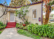 Thumbnail 6 of 6 - A house with a red door and a red staircase leading to it.