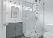 Thumbnail 9 of 42 - A white bathroom with a walk in shower and a toilet.