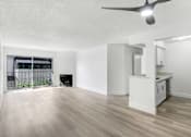 Thumbnail 11 of 24 - A spacious room with a ceiling fan and light, hardwood floors, and a kitchenette with white cabinets.