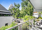 Thumbnail 12 of 24 - A balcony with a white railing overlooks a parking lot and trees.