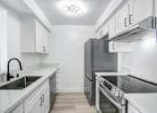 Thumbnail 14 of 24 - A modern kitchen with a refrigerator, stove, and sink.
