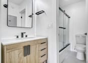 Thumbnail 20 of 24 - A bathroom with a white toilet and a sink with a mirror above it.