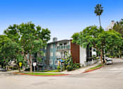 Thumbnail 21 of 24 - A street view of a residential area with a blue building on the left and a white building on the right.