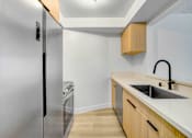 Thumbnail 4 of 24 - A modern kitchen with a stainless steel refrigerator and wooden cabinets.