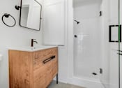 Thumbnail 6 of 24 - A bathroom with a wooden vanity and a white toilet.