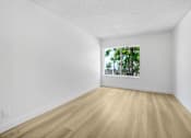 Thumbnail 7 of 24 - A room with wooden floors and a window showing trees outside.
