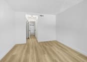 Thumbnail 8 of 24 - A hallway with a wooden floor and white walls.