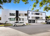 Thumbnail 1 of 4 - a white car parked in front of a white and black apartment building