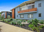 Thumbnail 1 of 3 - A modern two-story building with a balcony and a garden in front.