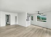 Thumbnail 2 of 10 - A room with a ceiling fan and a window showing trees outside.