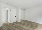 Thumbnail 6 of 10 - A room with white walls and wooden flooring with two doors.