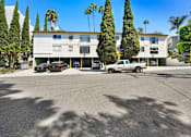 Thumbnail 8 of 10 - A white building with a parking lot in front of it.