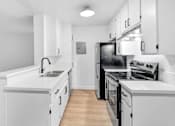 Thumbnail 3 of 17 - a white kitchen with white cabinets and black appliances
