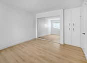 Thumbnail 5 of 17 - a bedroom with white walls and wood floors and a closet