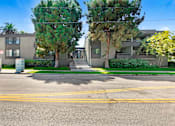 Thumbnail 4 of 12 - A street view of a residential area with two houses, trees, and a clear sky.