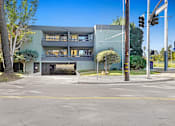 Thumbnail 6 of 12 - A modern building with a grey facade and a black gate.