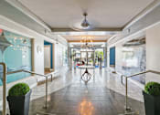 Thumbnail 2 of 5 - A long hallway with a table and chairs in the middle.