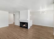 Thumbnail 3 of 13 - A living room with a fireplace and wood flooring.