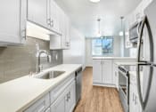 Thumbnail 4 of 13 - A kitchen with white cabinets and a stainless steel refrigerator.