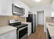 Thumbnail 5 of 13 - A kitchen with white cabinets and black appliances.