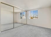 Thumbnail 6 of 13 - A room with a sliding glass door leading to a balcony with a view of palm trees.