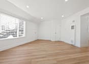 Thumbnail 1 of 28 - A spacious room with wooden flooring and white walls.