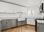 Thumbnail 3 of 28 - A kitchen with white cabinets and a wooden floor.