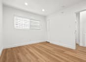 Thumbnail 4 of 28 - A room with wooden flooring and white walls.