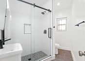 Thumbnail 7 of 28 - A white sink is on the left of a glass shower stall.