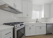 Thumbnail 3 of 9 - A modern kitchen with white cabinets and a stainless steel dishwasher.