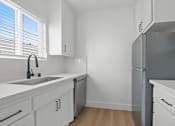 Thumbnail 4 of 9 - A kitchen with white cabinets and a grey refrigerator.