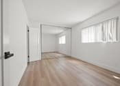 Thumbnail 8 of 9 - A room with a wooden floor and a white door.