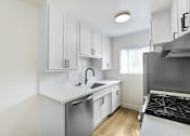 Thumbnail 20 of 28 - A kitchen with white cabinets and a stainless steel sink and stove.