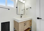 Thumbnail 25 of 28 - A bathroom with a sink, mirror, and cabinets.
