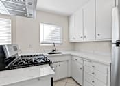 Thumbnail 11 of 28 - A kitchen with white cabinets and a black stove top.