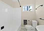 Thumbnail 15 of 28 - A white bathroom with a toilet, tub, and window.