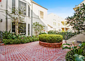 Thumbnail 2 of 3 - A red brick pathway leads to a white building with a black door.